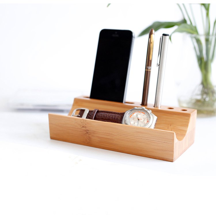 Angled view of a bamboo desk organizer featuring slots for a smartphone, pens, and a wristwatch — eco-friendly workspace tidy for modern professionals.