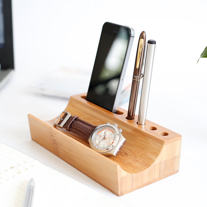 Bamboo desk organizer with slots for smartphone, pens, and wristwatch, ideal for minimalist and eco-conscious workspaces.