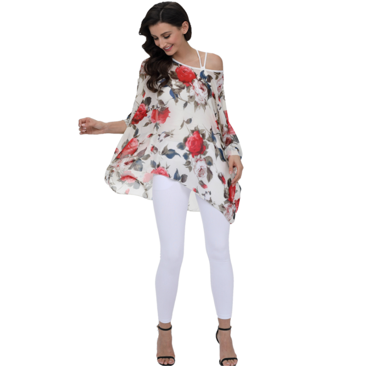 Woman wearing a flowy off-shoulder floral chiffon blouse with red and white roses, featuring an asymmetrical hem and white strap detail, paired with white leggings and heels. Perfect for spring or summer fashion.
