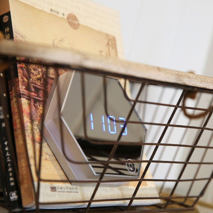 Hexagon digital mirror clock with blue LED display, neatly placed in a wire basket bookshelf with vintage books, combining modern function with rustic décor style.
