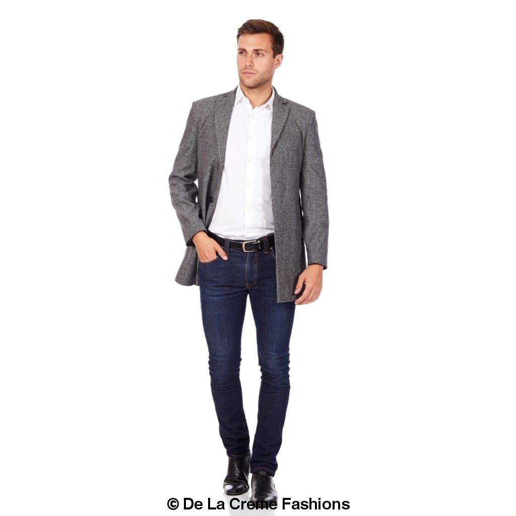Man modeling a grey single-breasted slim-fit overcoat paired with a white button-up shirt, dark wash jeans, and black leather boots—ideal for modern, smart-casual outfits. © De La Creme Fashions