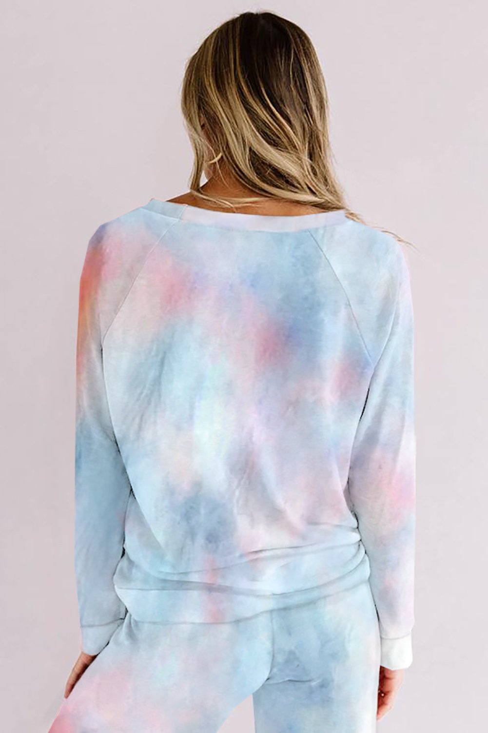 Back view of a woman wearing a pastel tie-dye loungewear set in cool hues of blue, pink, and purple. The soft sweatshirt and matching pants have a relaxed, cozy fit, perfect for lounging at home.