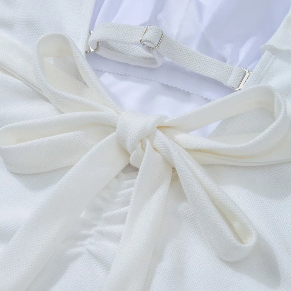 Detailed close-up of the back waist tie and adjustable buckle strap on a white one-shoulder ruffle one-piece swimsuit, highlighting fabric texture and fit.