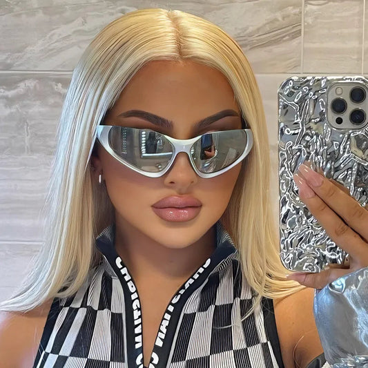 Woman with long platinum blonde hair taking a mirror selfie, wearing futuristic mirrored wraparound sunglasses and a bold black-and-white patterned outfit.