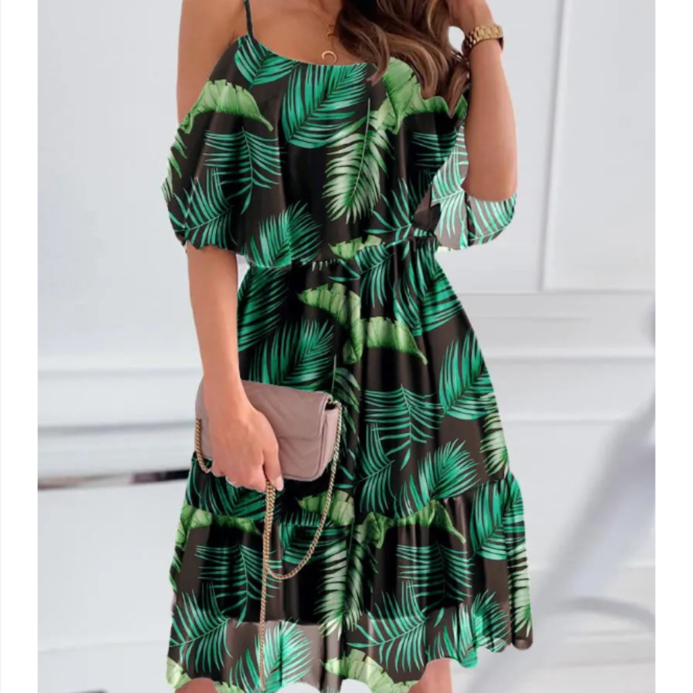 Woman wearing a black midi dress with green tropical leaf print, featuring off-the-shoulder ruffle sleeves and adjustable spaghetti straps, perfect for summer or vacation styling.