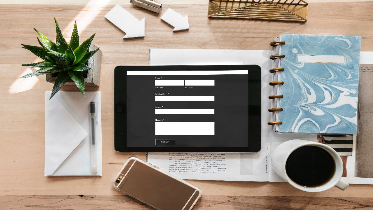 Organised desk flat lay with contact form on tablet, notebook, coffee, and tech — reflecting focus, clarity, and calm productivity